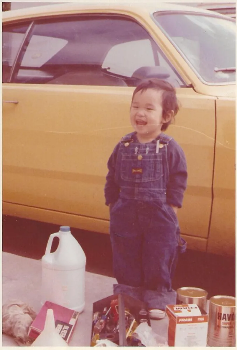 Before: faded snapshot of a toddler in overalls standing beside a yellow car