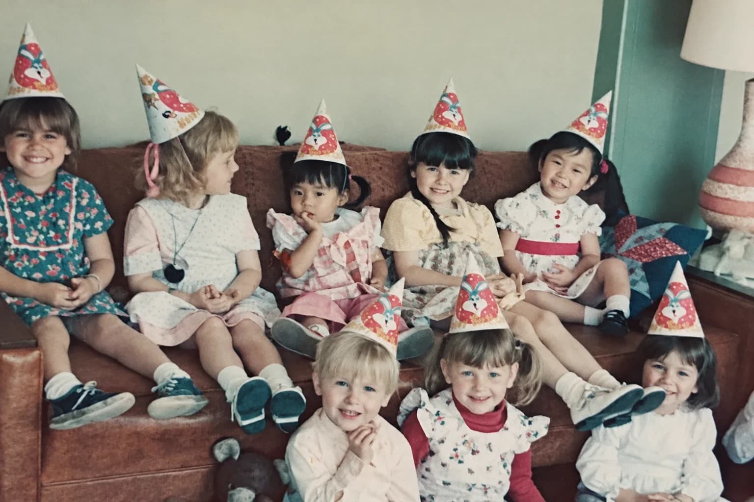 Enhance: faded color snapshot of children in party hats sitting on a couch